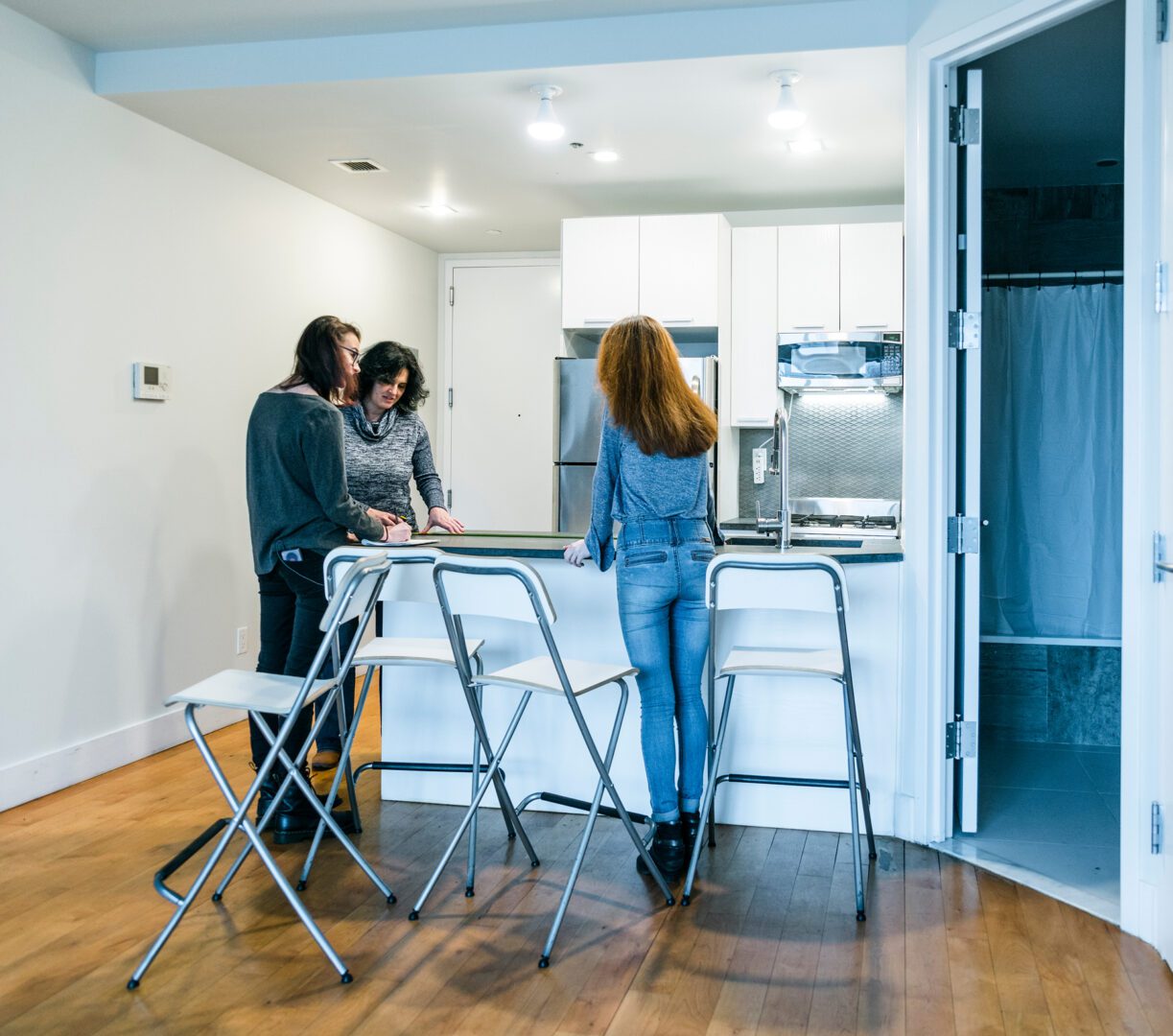 GettyImages-997287224 Three people talking in a modern kitchen.