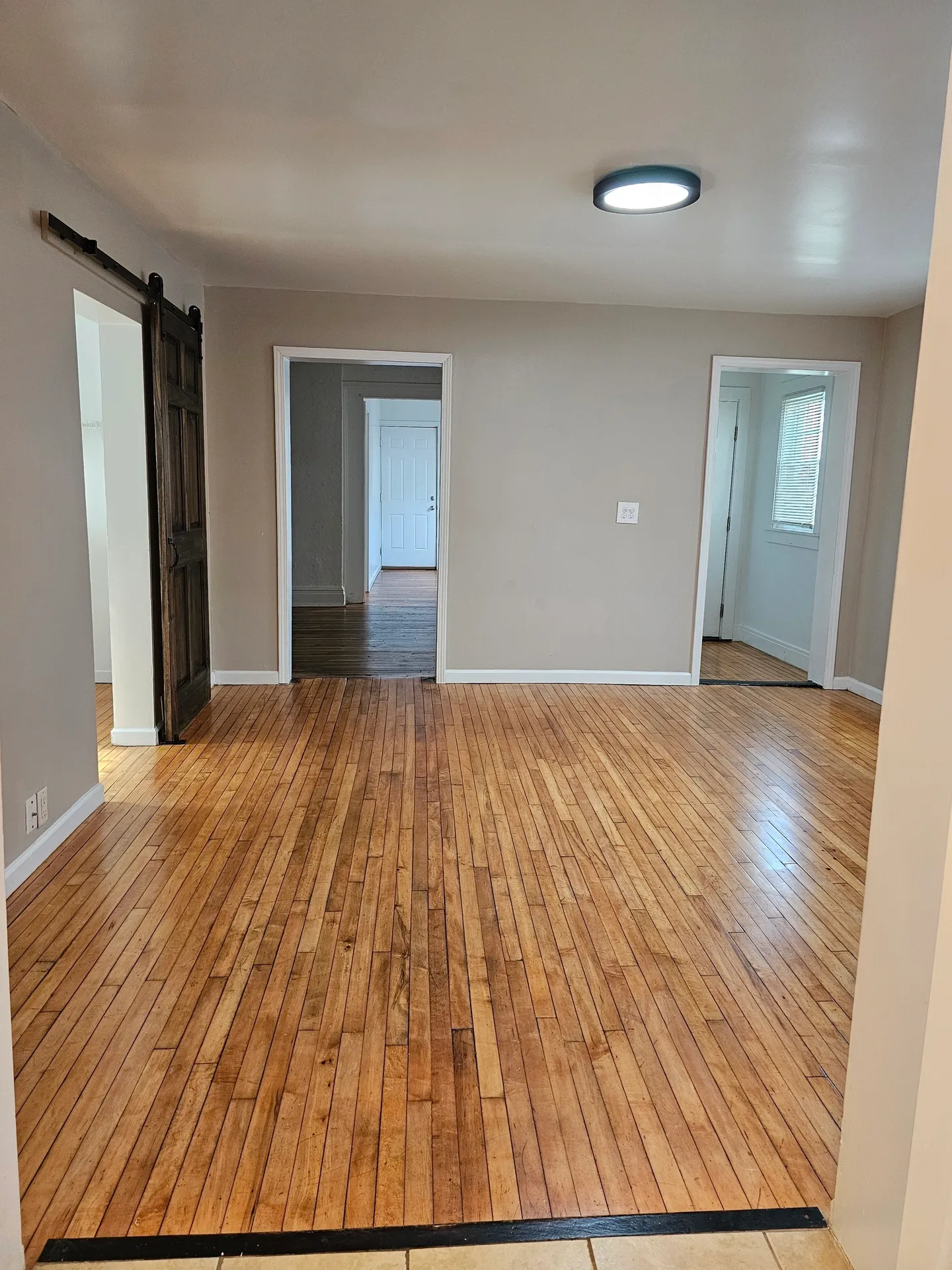 Spacious room with wooden flooring and door.