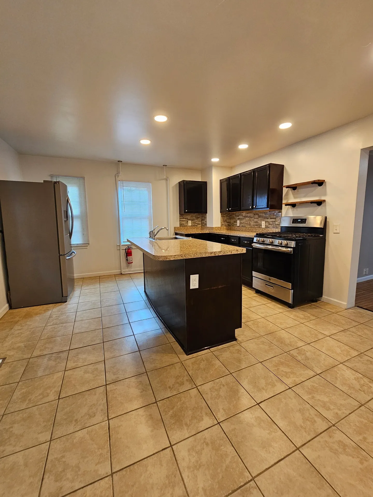 Modern kitchen with island and tiled floor.