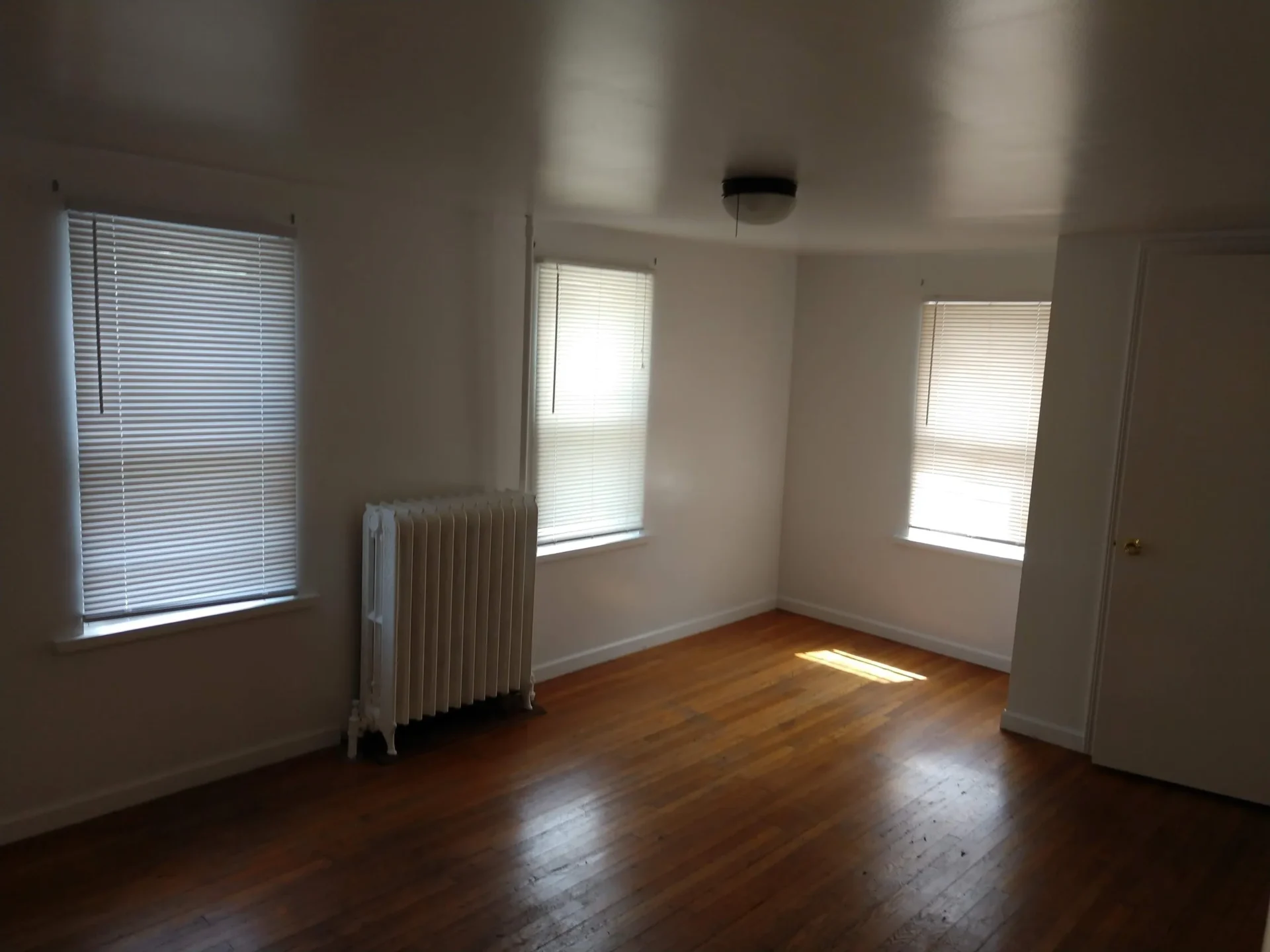 Empty room with hardwood floors and blinds.