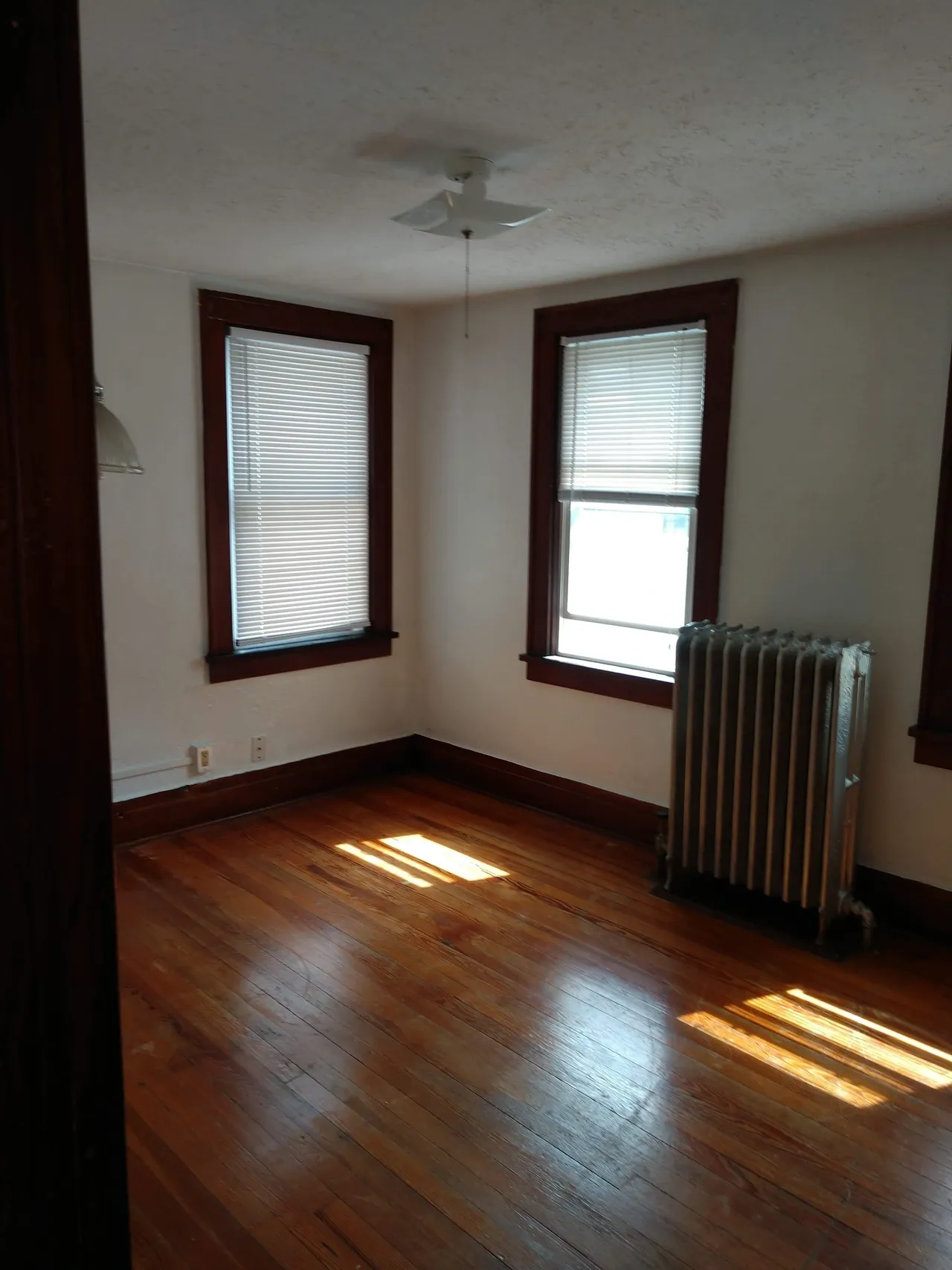 Empty room with wooden floor and windows.