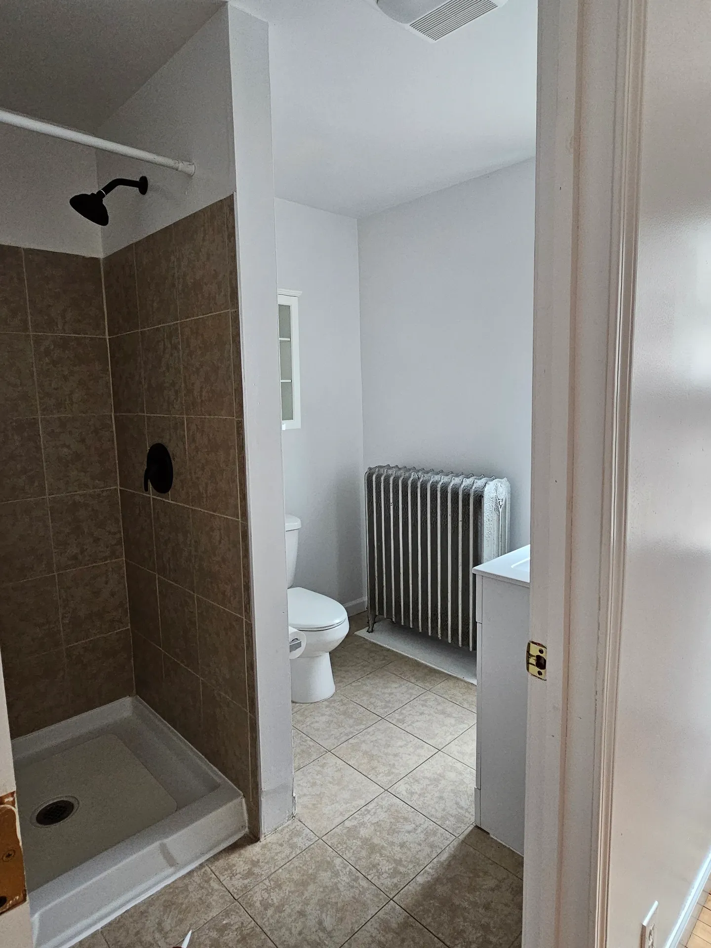 Small bathroom with shower and radiator.